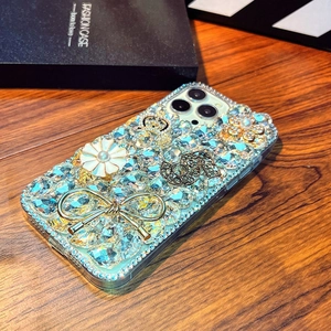 Macro detail of luxury iPhone case featuring rhinestone flowers and golden bow decoration