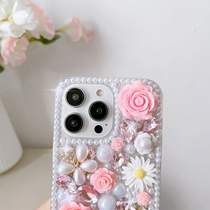 Détail macro d'une coque iPhone luxe avec roses 3D, marguerites et cristaux roses