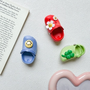 Detail view of mini EVA clog charms in red, blue, and green with floral smile patterns