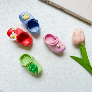 Close-up of mini EVA slipper phone stands in blue, red, pink, and green with cartoon charms