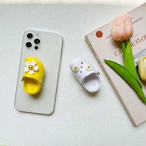 Miniature clog shaped phone socket with floral charms attached to a smartphone