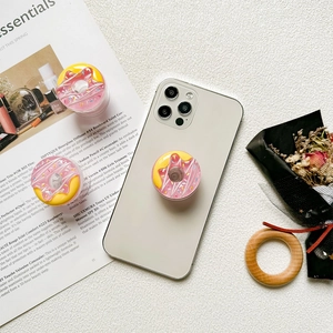 3D donut phone socket grip with colorful sprinkles on a gold smartphone case
