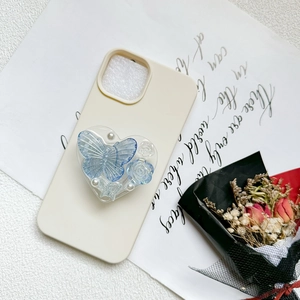 Cream phone case with a heart-shaped resin stand featuring blue butterfly and pearl accents