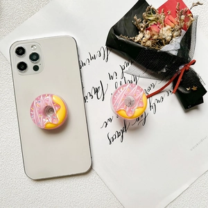 Detail of pink donut phone socket grip with colorful sprinkles on a white smartphone