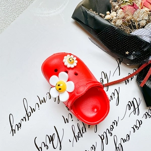 Detail view of a red clogs-style silicone phone holder with white smile daisy charms