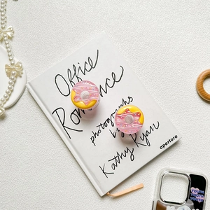 Detail of pink and yellow 3D donut phone grip stand with rainbow sprinkles on a book