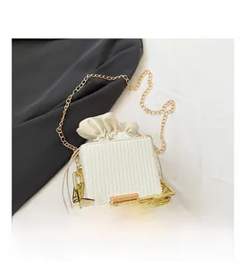 Top view of white woven bucket bag featuring gold chunky handle and drawstring closure