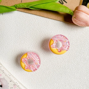 Close-up of pink and yellow donut phone grip with sprinkles on a minimalist background