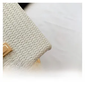 Detail view of white woven handbag fabric with premium golden metal hardware accents