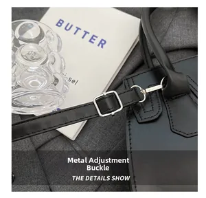 Detail of silver metal adjustment buckle and leather strap on a minimalist black bag