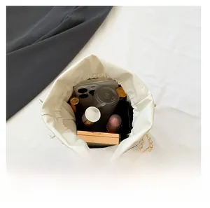 Internal capacity of the white leather bucket bag showing smartphone and cosmetics