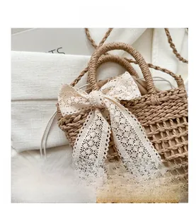 Detail der handgewebten Strohtasche mit Hohlgeflecht und eleganter beiger Spitzenschleife