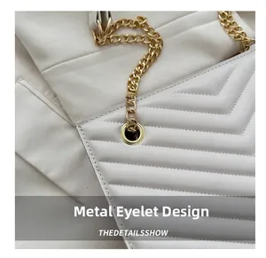 Detail of white quilted leather tote bag featuring gold chain and hardware eyelet design