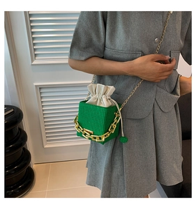 Detail of green woven bucket bag featuring gold chunky chain and drawstring inner pouch