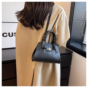 Black leather crossbody bag with silver twist lock shown on model with trench coat