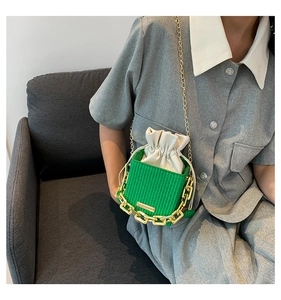 Detail of green woven bucket bag with white drawstring liner and gold chain strap