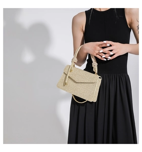 Detail der beigen Strohhandtasche mit gewebtem Knotengriff und Lederriemen