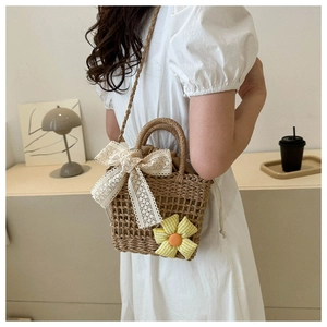 Detail of handmade straw bag featuring lace bow, sunflower charm and drawstring pouch