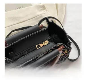 Close-up of smooth metal zipper and colorful woven texture on the black shoulder bag