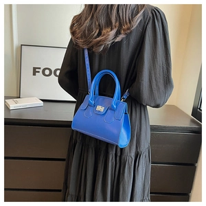 Detail view of vibrant blue crossbody bag with silver twist lock and round handle straps