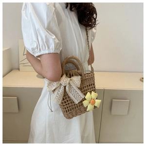 Detail der handgewebten Stroh-Eimertasche mit Spitzenschleife und Stoffblumen-Dekor