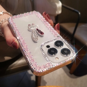 Close-up of luxury clear case with pink resin roses and sparkling rhinestone pendant