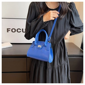 Detail of bright blue leather handbag with silver rotary buckle on a black background