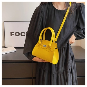 Detailed view of yellow crossbody bag with silver twist lock on a black dress