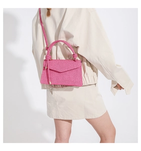 Detail einer leuchtend rosa geflochtenen Handtasche mit geflochtenem Griff und Gurt