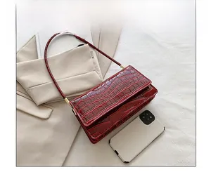Comparaison de taille détaillée d'un sac à main rouge effet crocodile avec un smartphone
