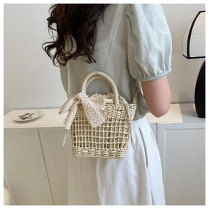 Detail of hand-woven straw bucket bag with lace bow and drawstring inner lining