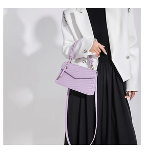 Detail einer lila gewebten Handtasche mit Schultergurt und schickem Tragegriff