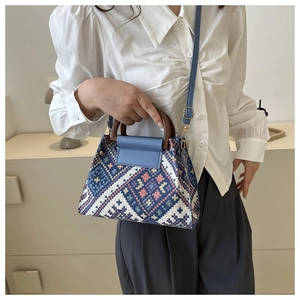 Close-up of ethnic woven pattern on handbag with round wooden handle and blue strap