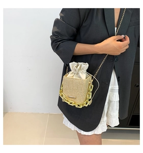 Close-up of straw bucket bag with gold chain strap and drawstring satin lining