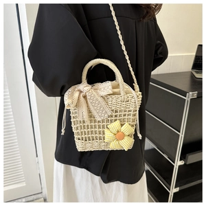 Detailansicht der Strohhandtasche mit Spitzenschleife und floralem Muster am Modell