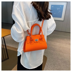 Close-up of bright orange crossbody bag featuring a silver twist lock and slim strap