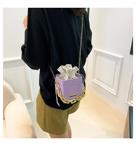 Detail of purple woven mini bucket bag with gold chain strap on a model's back