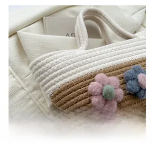 Détail du sac seau bicolore tressé avec des décorations florales en peluche douce