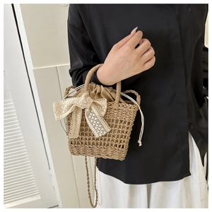 Detail of straw bucket bag featuring cream lace bow and drawstring closure for summer