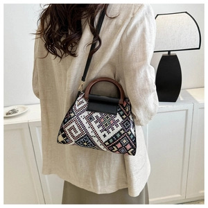 Detailed shot of ethnic geometric woven crossbody bag with round wooden handle and leather strap