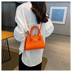 Detail of vibrant orange leather handbag with silver twist lock and minimalist design