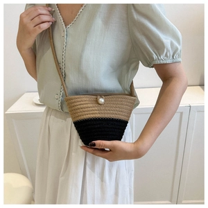 Dettaglio della borsa a secchiello tessuta a mano con chiusura a perla e design a contrasto