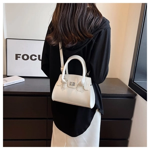 Rear view of a white minimalist trapezoidal handbag with silver clasp on a model