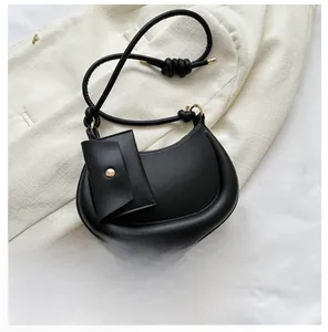 Detail of black crescent shoulder bag with mini pouch and phone for size reference