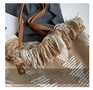 Close-up of woven tote bag showing fringe detail, leather handles and gold rivets