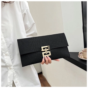 Close-up of black crocodile pattern clutch bag with a large golden geometric metal buckle