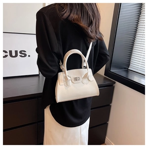 Detail of cream white leather handbag with silver lock shown on shoulder in urban setting