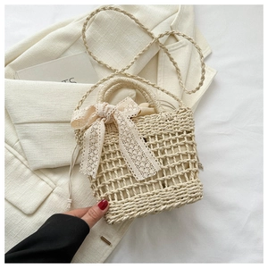 Detailed weave pattern of beige straw bucket bag featuring an elegant lace bow decoration