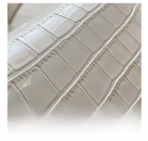 Détail rapproché du cuir gaufré blanc crème avec un motif pierre et une finition brillante
