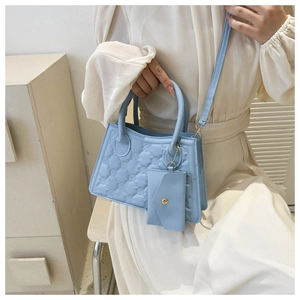 Detail of light blue quilted crossbody bag with M-pattern and detachable mini pouch
